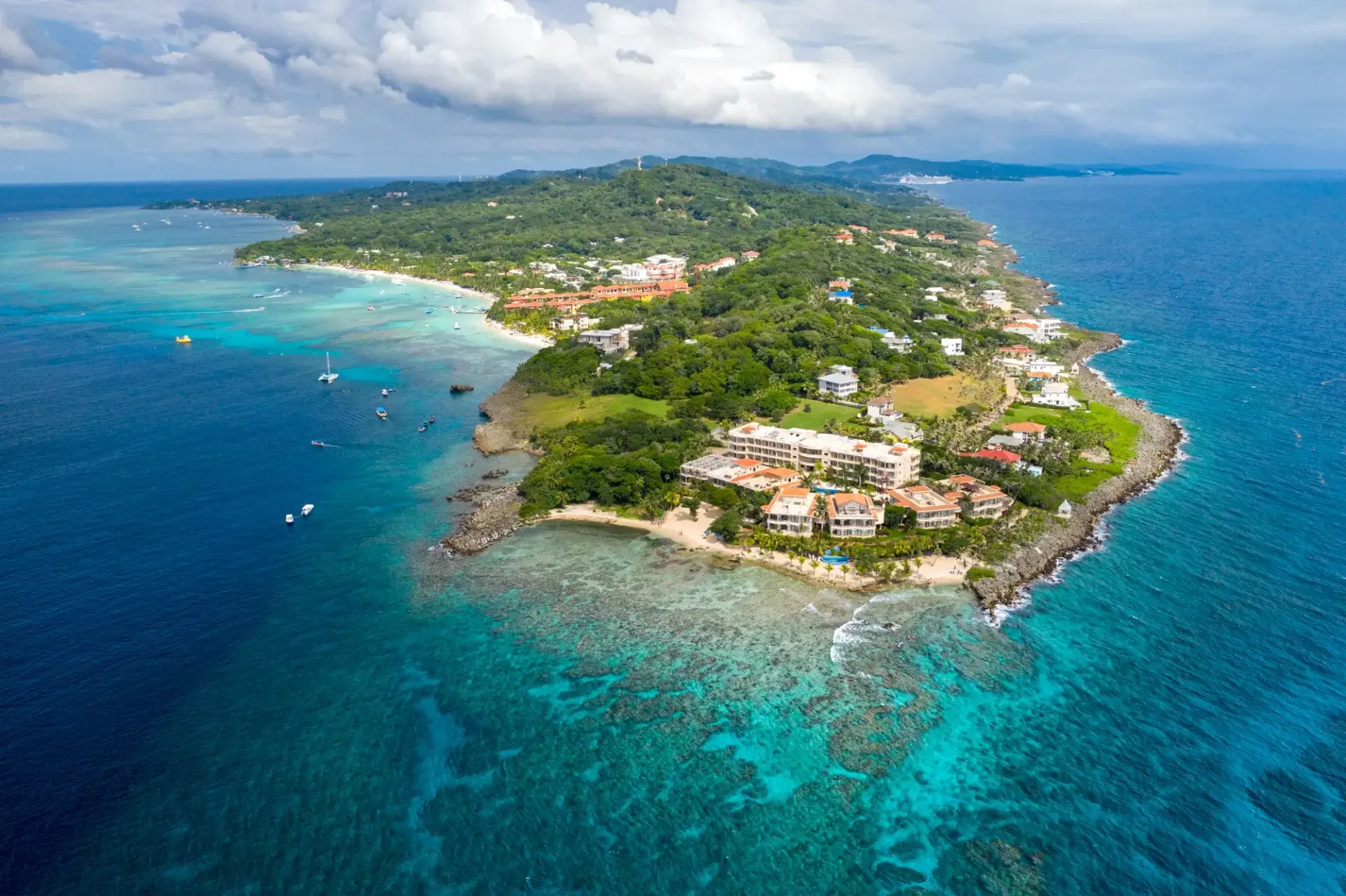 Aerial view of Roatan Honduras showing turquoise Caribbean water, reef, and lush green coastline