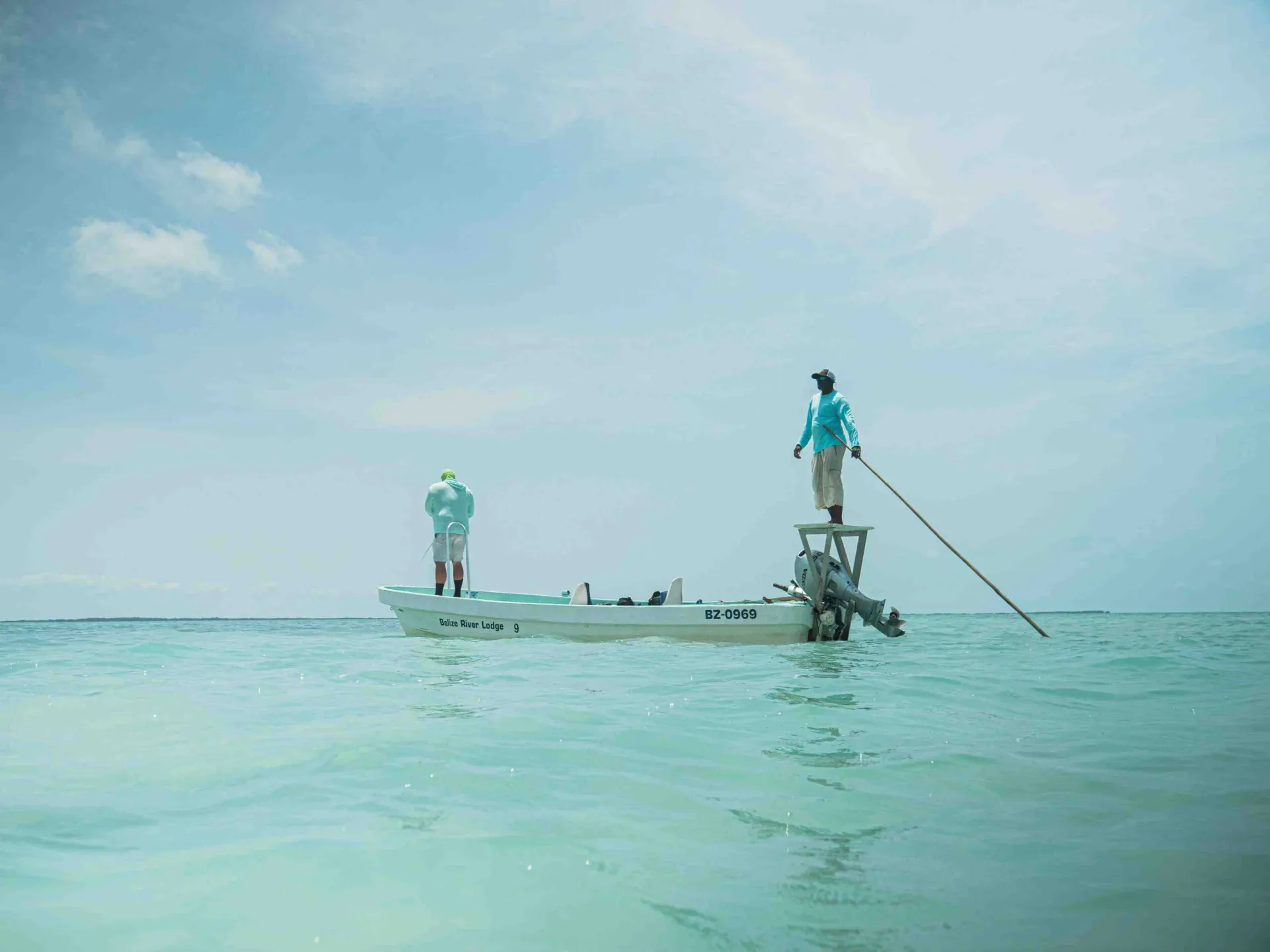 Roatan northwest flats from a fishing boat, clear turquoise water over white sand with mangrove edges in the distance